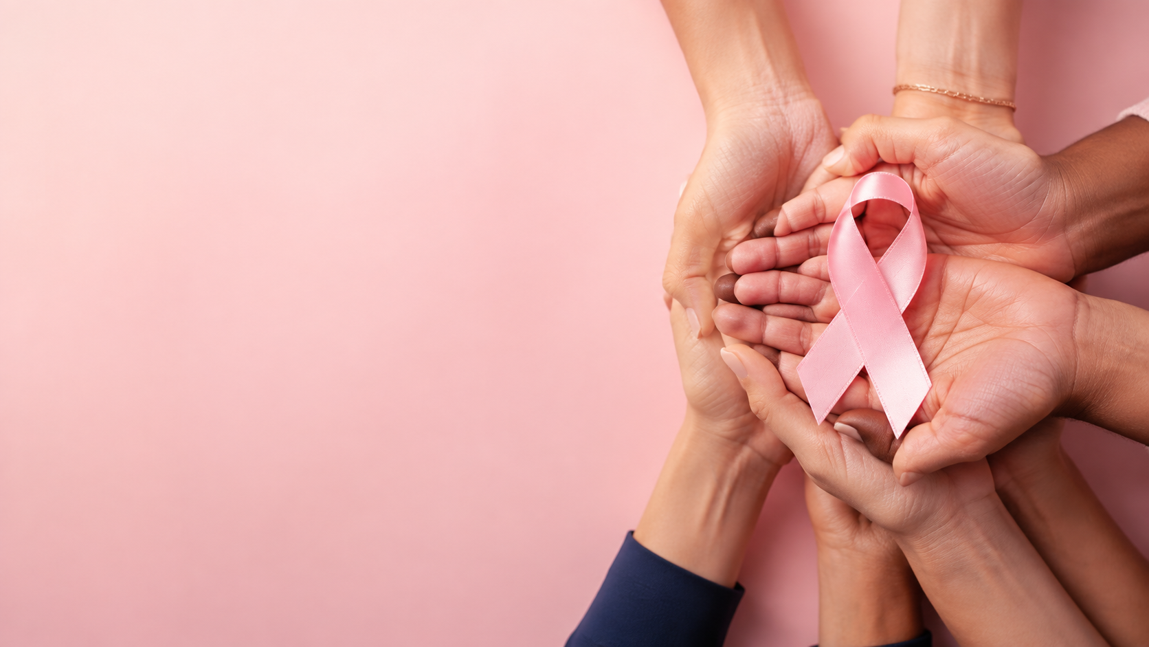 Mãos unidas segurando o laço rosa, símbolo da conscientização sobre o câncer de mama